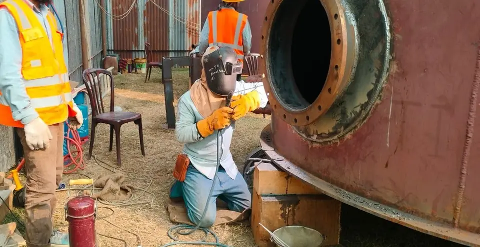 Welder fitting a new nozzle on a tank shell