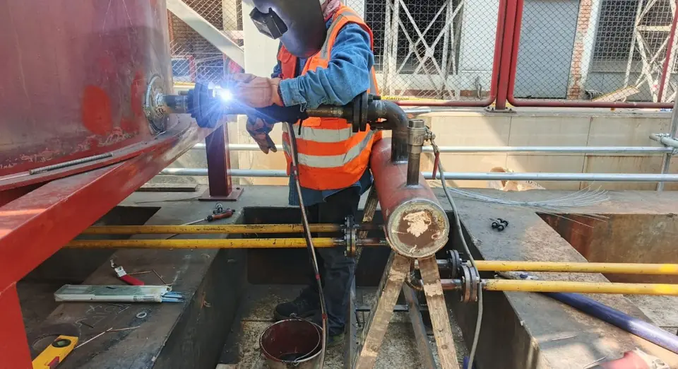 Welder working on an outlet spool at a fuel oil tank